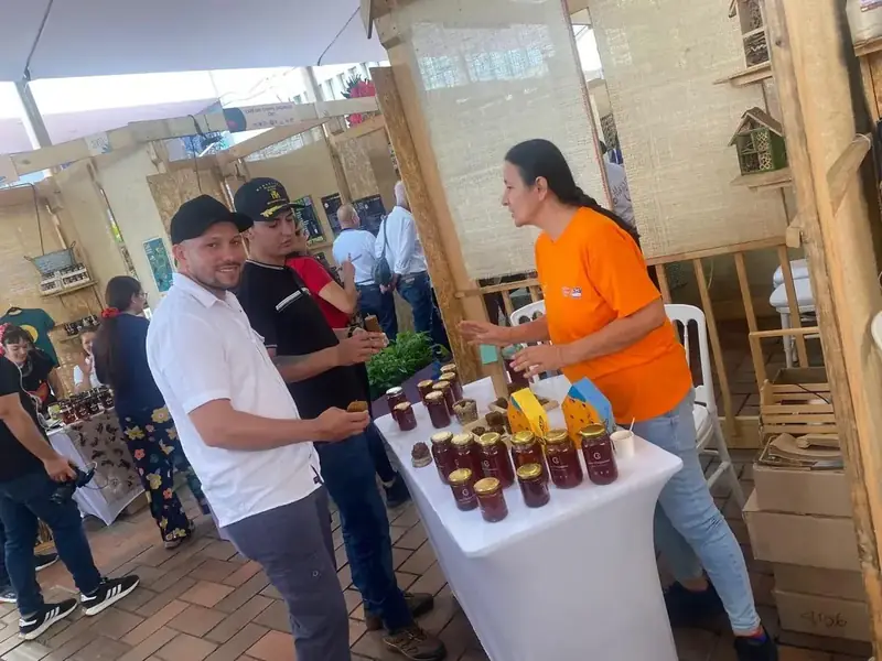 Visitantes conociendo la miel de la reserva en el stand